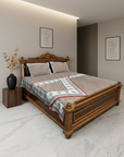 An ornate wooden bed frame with a carved headboard and footboard, dressed in a patterned beige and gray bedding set with red accents, set in a modern bedroom with marble flooring and minimalist wall art.
